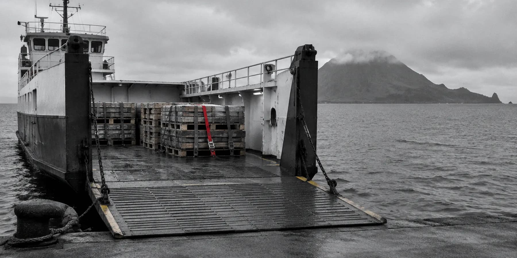 La rampa de un ferry de carga entre islas con palés esperando y una isla al fondo